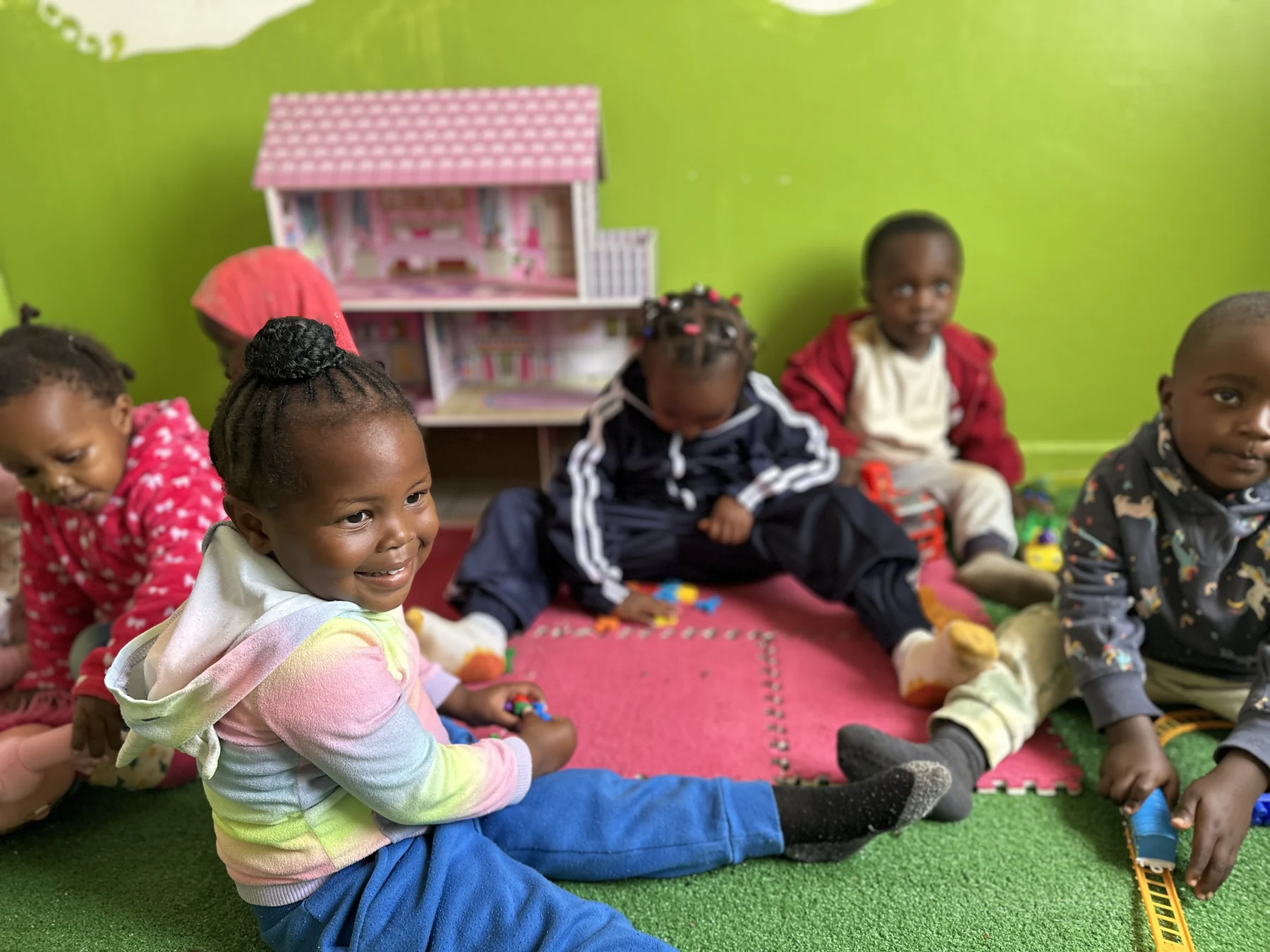 A smiling child playing with friends on the colourful floor mats