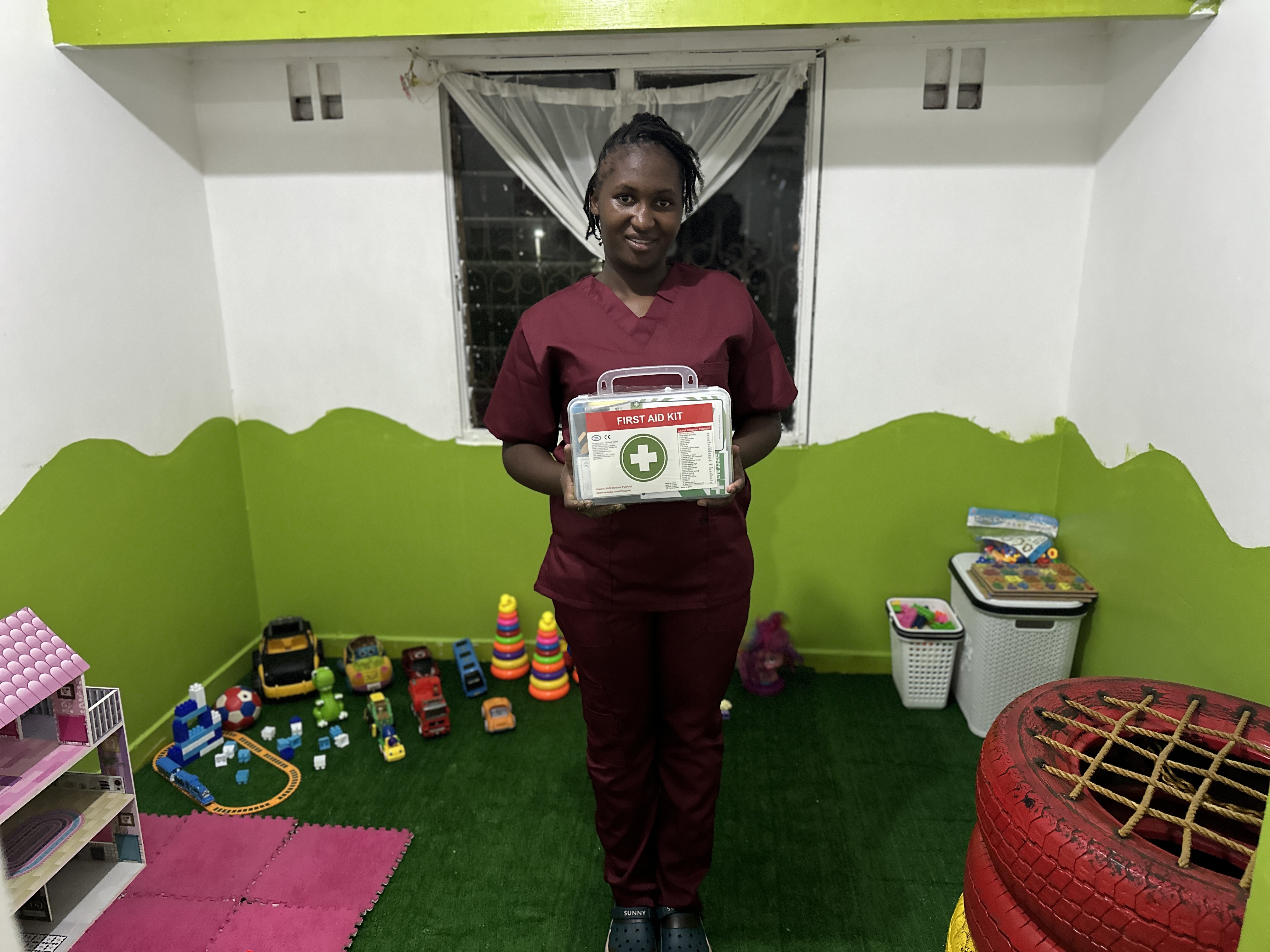 A member of the Little Heaven team holding a first aid kit in the playroom